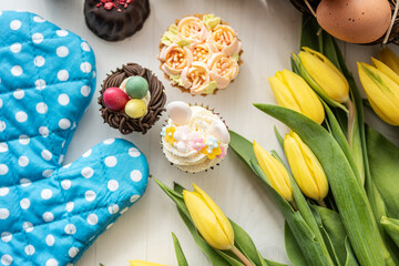 cute colorful spring easter egg shape cake tartlet muffin cupcake with yellow tulips easter concept 