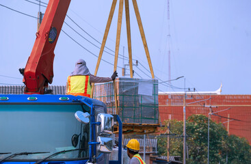 Two workers are transferring lot of concrete tiles floor on boom truck into road construction site