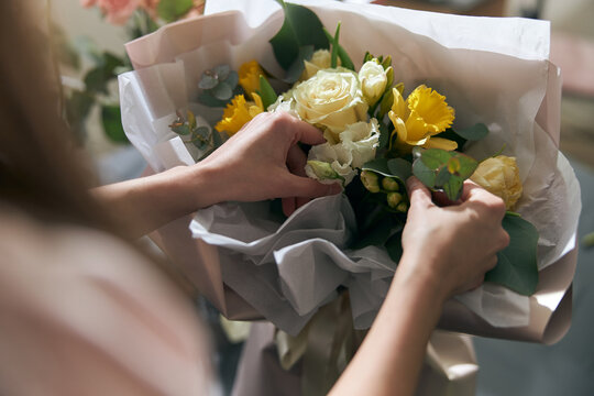 Nice and colorful bouqette of different flowers. Female florist hold it. She is in flower shop. Close up
