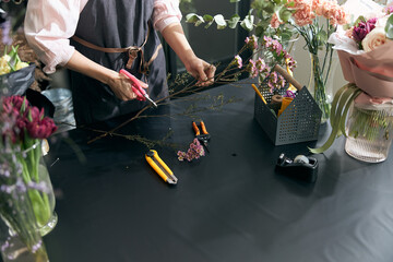 Woman sales flowers in flower shop. Florist woman working at flower shop. Portrait of successful modern florist wearing apron