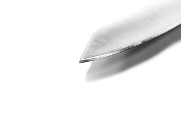 Monochrome image, sharp hunting knife with shadows on white background, focus on the tip of the knife.