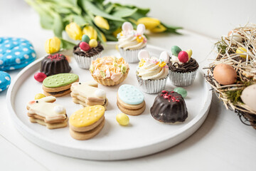 cute colorful spring easter egg shape cake tartlet muffin cupcake with yellow tulips easter concept 