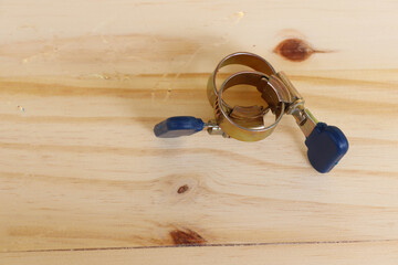 Blue metal adjustable hose clamps with copy space isolated on wooden background closeup.
