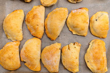 Frozen baked dumplings in dough on a baking sheet on baking paper, top view.