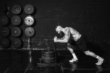 Young strong active sweaty muscular fit man with big muscles pushing heavy weight plates on the...