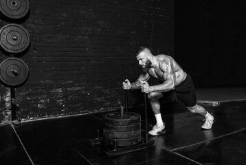 Young strong active sweaty muscular fit man with big muscles pushing heavy weight plates on the...