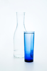 A transparent bottle and a blue glass with clean water are on the table.