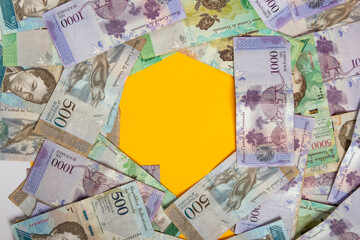 montones de dinero venezolano a la vista superior uno encima del otro con números de 500 y 1000 bolívares con un espacio de fondo amarillo, vista superior.