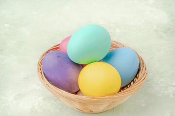colorful easter eggs in a basket on green background