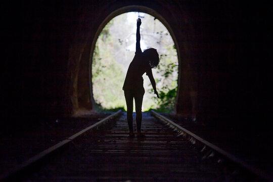 Rear View Of Silhouette Woman Walking In Tunnel