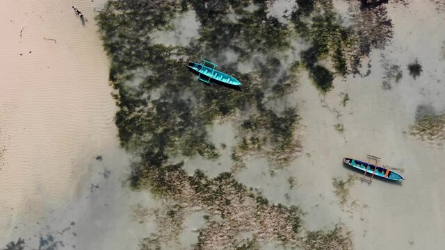 Local fishing boats sit in shallow water in Saint Marie, Madagascar. Aerial drone view.