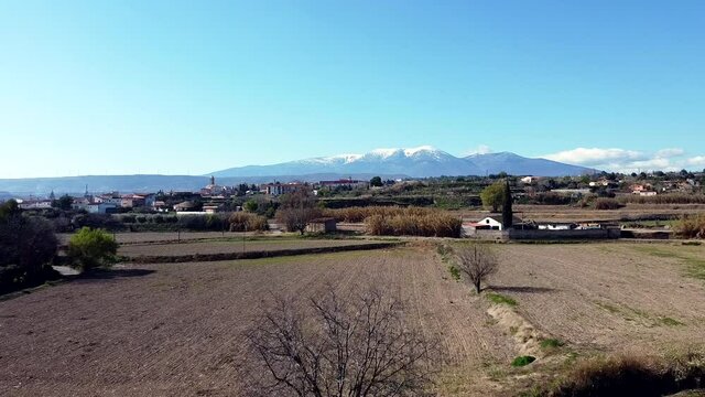 Drone aerial view of Moncayo snow mountain in Spain flying straight on across farms