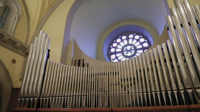 Gorgeous stainless steal organ pipe set up with a round stain glass window in the background at the St. Columban's Church in Cornwall, Ontario, Canada.
