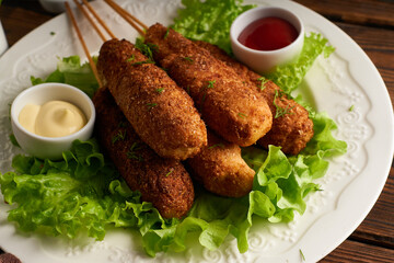 Tasty corn dog with sauce and salad served on white plate