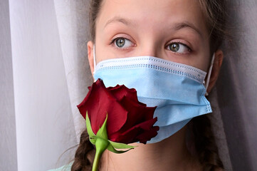 girl in protective medical mask with red rose, close-up portrait