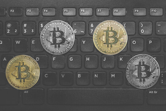 Tokens de bitcoin prata e ouro em cima de um teclado preto.