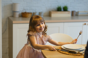 Small girl sets the table for a meal