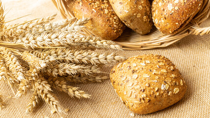 Freshly baked bread. Fresh loaf of rustic traditional bread with wheat grain ear or spike plant on linen texture background. Rye bakery with crusty loaves and crumbs. Healthy Food concept.
