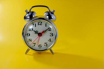 old mechanical alarm clock lies on a yellow background.