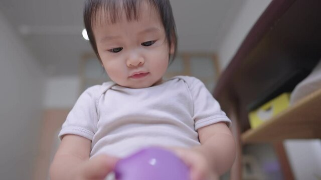 Portrait of cute little baby girl intently playing with a little purple hippopotamus toy at home, 2yrs toddler is cheerfully playing and talking with her imagined friend, imagination creation ability