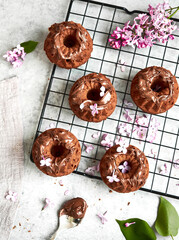 Baking, lilac, spring. Delicious sweet chocolate cupcakes with cream on top. Filled with chocolate. Surrounded by fresh lilacs. On a concrete countertop. Gray background. Space for the text. Content.