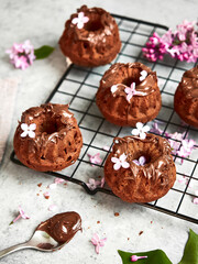 Baking, lilac, spring. Delicious sweet chocolate cupcakes with cream on top. Filled with chocolate. Surrounded by fresh lilacs. On a concrete countertop. Gray background. Space for the text. Content.