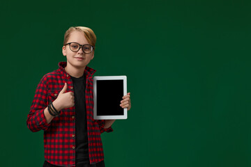 child boy in red checkered shirt shows empty tablet