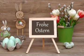 Osterkarte:Osterdekoration und eine Tafel mit dem Schriftzug Frohe Ostern