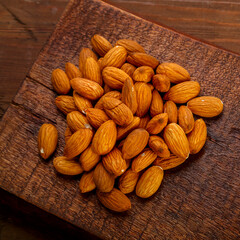 A handful of nuts are scattered on a board on a wooden table.