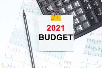 Text 2021 BUDGET on NOTEBOOK. NOTEBOOK, CALCULATOR PENCIL on white background.