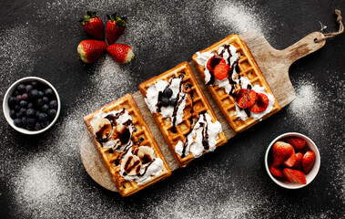 Sweet waffles(gofry) on the wooden desk with cream an fruits