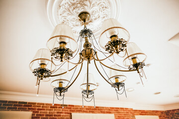 The chandelier hangs on the ceiling. Beautiful vintage lamp in the interior of the apartment. apartment design. lighting in the house. Boho style. Elegant fixture.