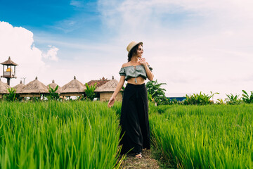 Young woman walking in green field and admiring scenery