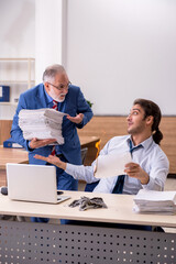 Obraz premium Young male employee and old boss burning papers at workplace