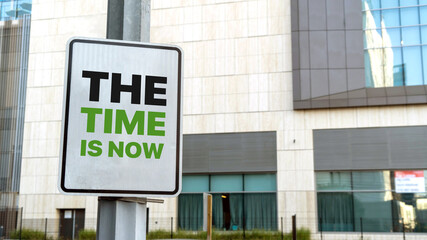 Obraz premium The Time is now sign in a downtown city setting