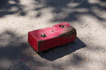 High angle close-up view of one of the red wooden blocks attached to the pavement to mark the edge of an unsecured concrete driveway bridge without rails 