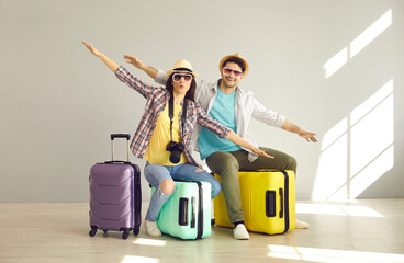 Portrait of attractive young cheerful couple travelers humorous gesture flying like plane showing...