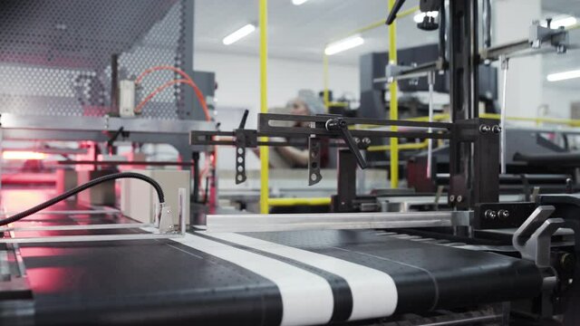 Conveyor line for the production of boxes. Machine carves and bends cardboard boxes from sheets of cardboard. Enterprise for the production package