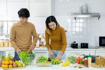 Asian young couple preparing a meal chopping vegetables in kitchen at home, healthy lifestyle.