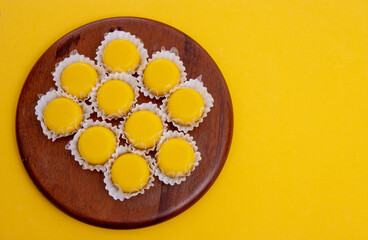 Sweet quindim in wooden dish on yellow  background