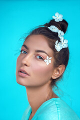 portrait of a beautiful, cute girl on a turquoise bright background with white flowers