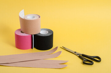 Kinesiological multi-colored tapes for fixing muscles during sports and after injuries on a yellow background with copy space.