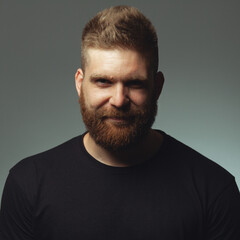 Fototapeta premium Fabulous at any age. Portrait of smiling 35-year-old man posing over gray background in black t-shirt. Close up. Hipster style. Red hair, modern haircut. Studio shot