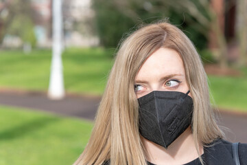 retrato de mujer rubia con ojos claros y mascarilla negra mirando a camara 