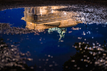 brandenburg gate reflected in a rain puddle at night	