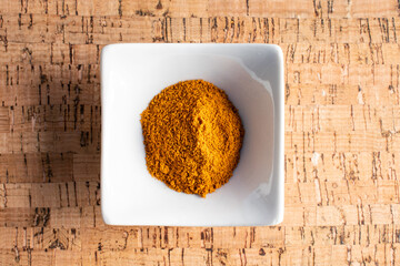 turmeric in a small white bowl on cork background
