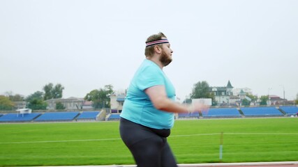 Hard cardio workout for a obese man running fast in the stadium to loose the weight concept of a healthy lifestyle