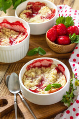 Summer dessert home cooking. Strawberries crumble in a baking dish and fresh strawberries on a wooden rustic table.