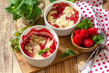 Summer dessert home cooking. Strawberries crumble in a baking dish and fresh strawberries on a wooden rustic table.