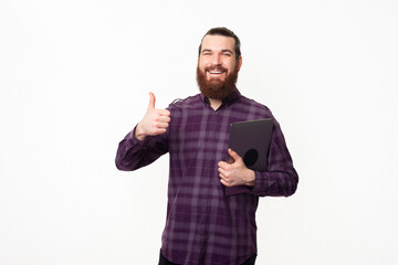 Fototapeta premium Photo of happy bearded student man showing thumb up and holding laptop